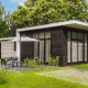Udendørs billede af Cosy Cabin med moderne sort og hvid facade, grøn græsplæne og havemøbler.