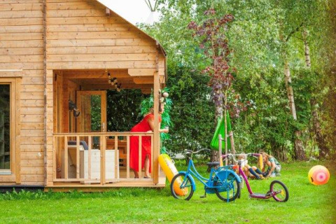 Safaritent Jungle huisje bij Beloofde Land in Nederland met fietsen, speelgoed en kinderen op het gras.