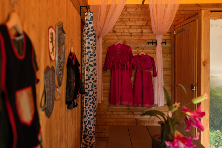 Interior of Ridder & Prinsessen safari tent at Beloofde Land, Netherlands, with red dresses hanging inside.