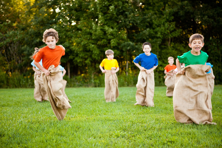 Children playing a sack race on grass near trees at Ridder & Prinsessen huisje in Beloofde Land, Netherlands.