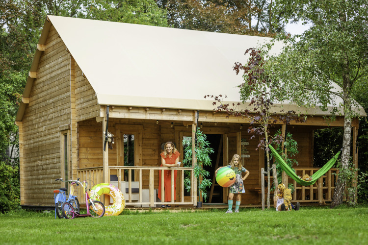 Gezin geniet buiten voor safaritent Konijntje huisje op Beloofde Land in Nederland, kinderen spelen.