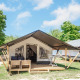Glampingverblijf met moderne tent, houten terras, buitensalon en omgeven door groene natuur.