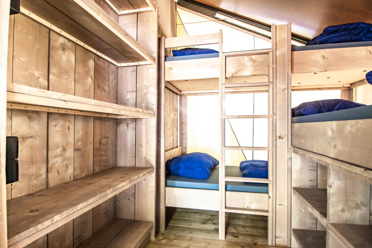 Innenraum eines Safaritent basic mit Etagenbetten und Regalen im Beloofde Land, Niederlande, tagsüber.