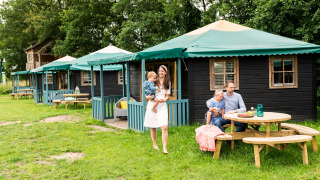 Family enjoys outdoor time at a Nature House called Forest cottage, featuring green roofs and picnic tables.