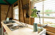 Forest cottage kitchen at Beloofde Land, Netherlands, with sink, stovetop and window views of nature.
