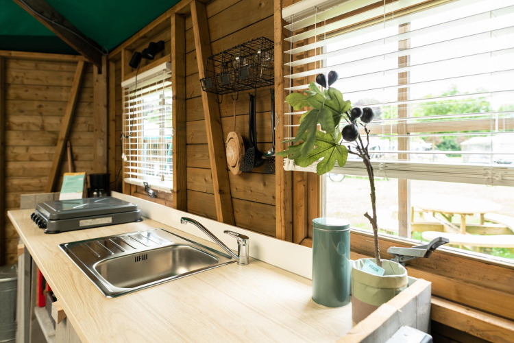 Forest cottage kitchen at Beloofde Land, Netherlands, with sink, stovetop and window views of nature.