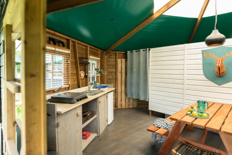 Imagen interior de Forest cottage en Beloofde Land, Países Bajos, con cocina de madera y mesa de picnic.