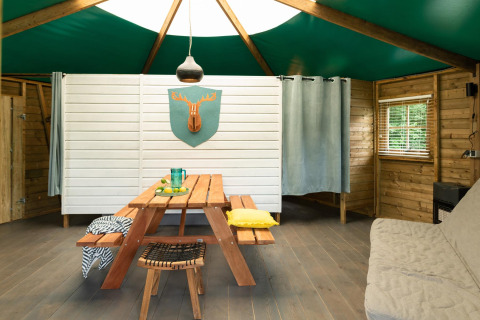 Vista interna di un cottage nella foresta al Beloofde Land, Paesi Bassi, con tavolo da picnic e decoro cervo.