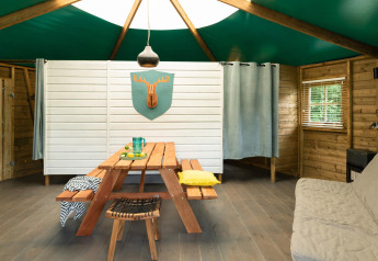 Vista interior de una cabaña en el bosque en Beloofde Land, Países Bajos, con mesa de pícnic y decoración.