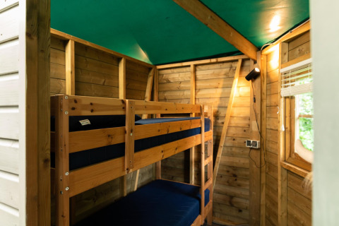 Interior of a cozy forest cottage with wooden bunk beds and green ceiling at Beloofde Land, Netherlands.