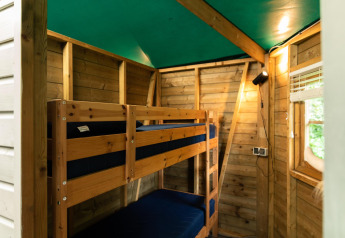 Interno di un accogliente cottage di legno con letti a castello e soffitto verde a Beloofde Land, Olanda.