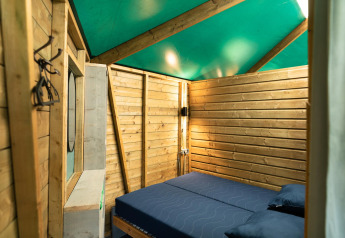Vista interna del Forest cottage al Beloofde Land nei Paesi Bassi con pareti in legno e letto doppio.