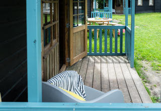 Veranda des Forest Cottage im Beloofde Land, Niederlande, mit Holztür und Blick auf grünen Rasen.