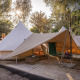 Solnedgang over tipi-teltet Solo Tipi på RØSTIG i Holland, omgivet af træer og udendørs hygge.
