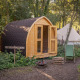 En hyggelig træhytte kaldet Premium - Solo Panoroma Pod ved RØSTIG, Holland, omgivet af grøn natur.