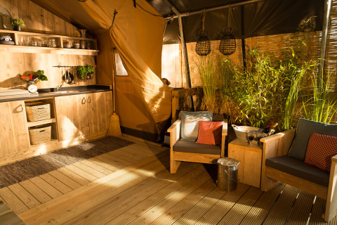 Sunlit interior of SunLodge Bintulu at Camping Village Poljana, Croatia, with rustic wood furniture and plants.