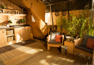 Sunlit interior of SunLodge Bintulu at Camping Village Poljana, Croatia, with rustic wood furniture and plants.