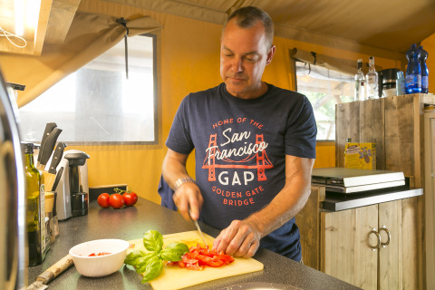Uomo che taglia pomodori nella cucina di SunLodge Bintulu al Camping Village Poljana, Croazia.
