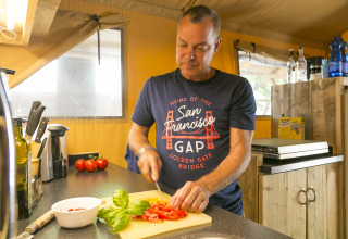 Hombre cortando tomates en la cocina de SunLodge Bintulu en Camping Village Poljana, Croacia.