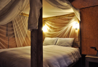 Cozy bed with mosquito net and warm lighting at SunLodge Bintulu, Camping Village Poljana in Croatia.