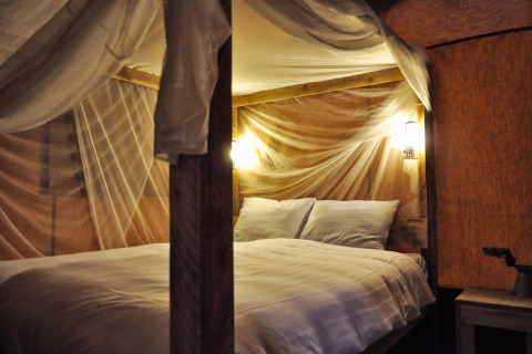 Cama cómoda con mosquitera e iluminación cálida en SunLodge Bintulu en Camping Village Poljana, Croacia.