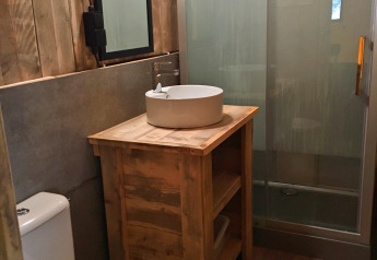 Salle de bain rustique avec panneaux bois, vasque ronde, toilettes et douche au SunLodge Bintulu, Croatie.
