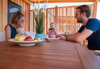 Famiglia che si gode un pasto insieme sulla terrazza della SunLodge Catalpa al Camping Village Poljana, Croazia.