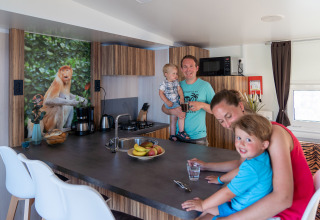 Familia disfruta en la cocina moderna de SunLodge Catalpa con foto de mono y frutero sobre la barra.