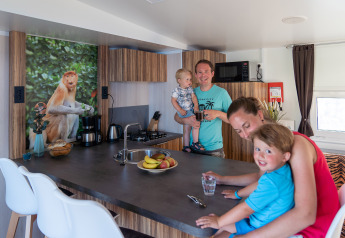 Famiglia trascorre del tempo in cucina alla SunLodge Catalpa con foto di scimmia e frutta sul bancone.