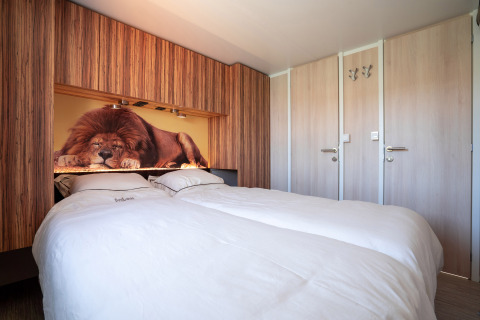 Camera accogliente al SunLodge Catalpa con letto matrimoniale e foto di un leone che dorme sopra la testata.