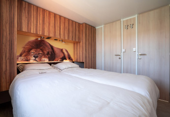 Comfortabele slaapkamer bij SunLodge Catalpa met tweepersoonsbed en foto van een slapende leeuw erboven.