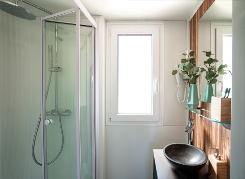 Moderne badkamer met douche, waskom, spiegel en raam in SunLodge Catalpa, helder en trendy afgewerkt.