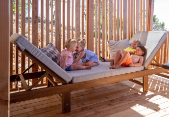 Vier kinderen spelen en ontspannen op een houten ligstoel bij SunLodge Catalpa, Camping Village Poljana, Kroatië.