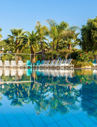 Piscina con tumbonas y palmeras en Camping Leï Suves, Provenza-Alpes-Costa Azul, Francia.