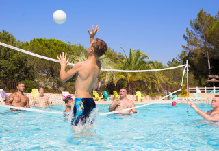 People playing pool volleyball under the sun at Camping Leï Suves holiday park in Provence-Alpes-Côte d’Azur, France.