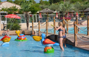 Bambini che giocano in una piscina bassa con giochi d'acqua colorati al Camping Leï Suves, Provence-Alpes-Côte d’Azur, Francia.