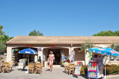 Cafetería exterior y supermercado en Camping Leï Suves en Provenza, Francia, bajo un cielo soleado.