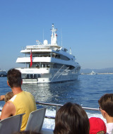 Turistas en un barco observan un gran yate cerca de Roquebrune-sur-Argens en Provenza-Alpes-Costa Azul, Francia.