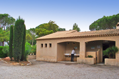 Udendørs sanitetsbygning på Camping Leï Suves i Provence-Alpes-Côte d’Azur, Frankrig, med en person ved vaskene.