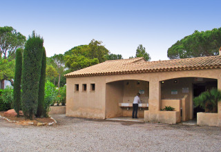 Edificio sanitario exterior en Camping Leï Suves, Provenza-Alpes-Costa Azul, Francia, persona usando los lavabos.