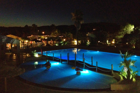 Foto nocturna de la piscina iluminada en Camping Leï Suves, un parque vacacional en Provenza-Alpes-Costa Azul, Francia.