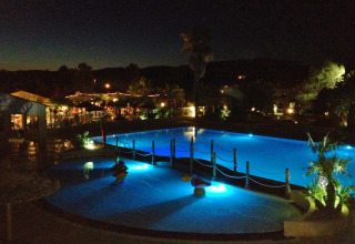 Nattefoto af det oplyste svømmebassin på Camping Leï Suves, en feriepark i Provence-Alpes-Côte d’Azur, Frankrig.