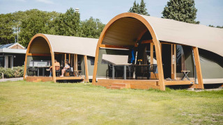 Tende lodge di lusso con veranda in legno al Camping de Bovenberg, Paesi Bassi, in una giornata di sole.