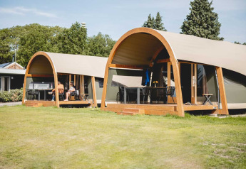 Luxury lodgetents with wooden frames and verandas at Camping de Bovenberg, Netherlands, on a sunny day.