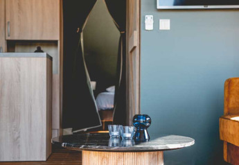 Salon moderne dans une tente safari de luxe au Camping de Bovenberg, Pays-Bas, avec table et télé.