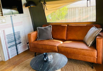 Luxury lodge tent at Camping de Bovenberg, Netherlands, featuring a brown sofa and modern decor.