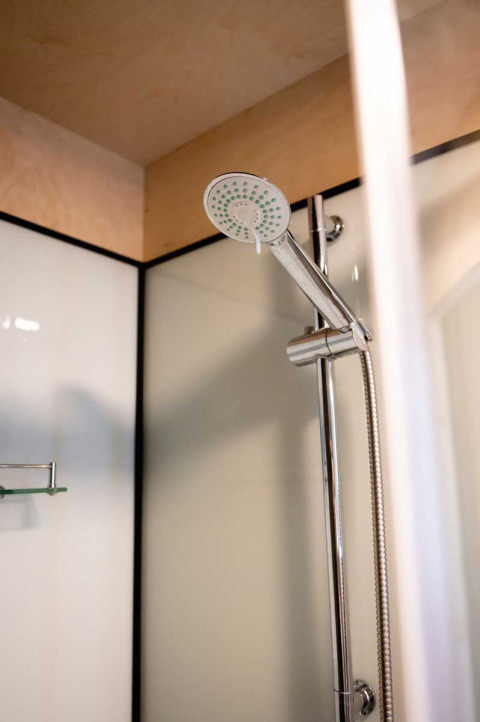 Dusche im Luxuszelt auf dem Camping de Bovenberg, Niederlande, mit moderner Ausstattung und Duschkopf.