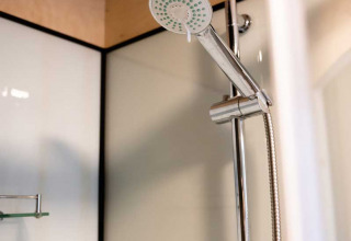 Dusche im Luxuszelt auf dem Camping de Bovenberg, Niederlande, mit moderner Ausstattung und Duschkopf.