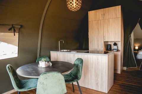 Moderne Küche und Esstisch mit grünen Stühlen in einem Luxus-Safarizelt auf Camping de Bovenberg, Niederlande.