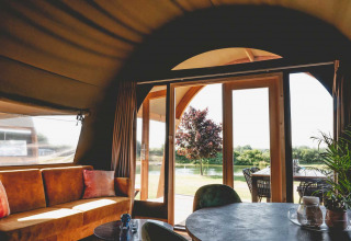 Vista interior de una tienda safari de lujo en Camping de Bovenberg, con sofá y terraza en Países Bajos.